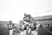 Minnesota Viking tackle Jim Marshall clutches the game ball as he is carried from the field by teammates Doug Southerland, left, and Scott Studwell after the Vikings had beaten Buffalo 10-3, in Bloomington, Minn., on Sunday, Dec. 9, 1979. (AP Photo/Jim Mone)